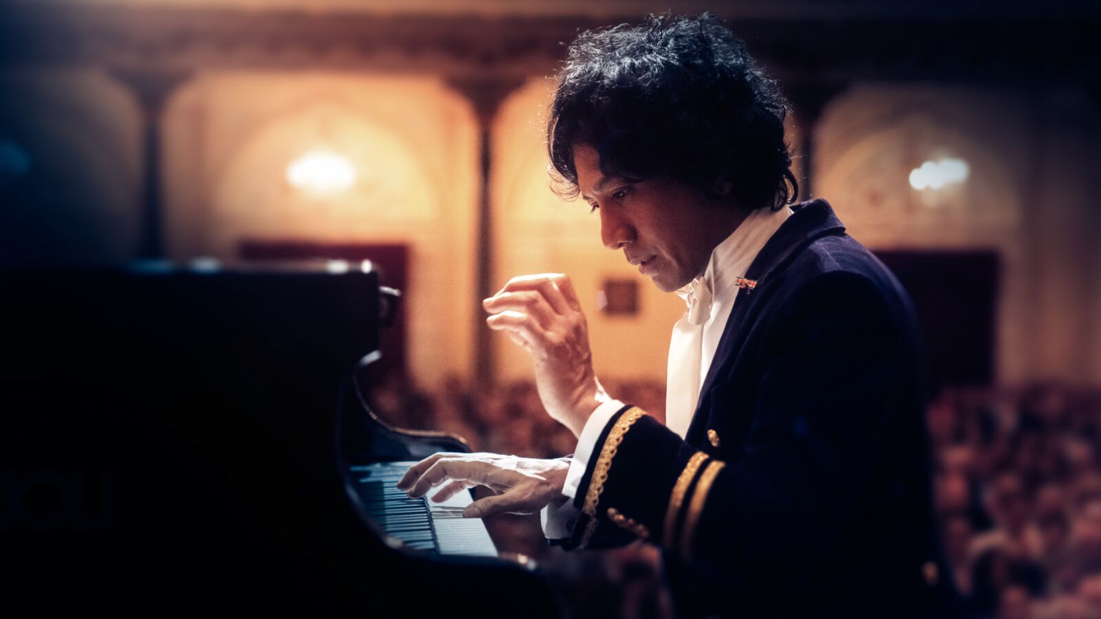 Foto van Wibi Soerjadi die pianospeelt in een theaterzaal.